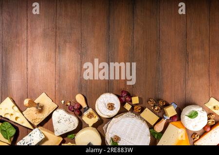 Verschiedene Käsesorten. Käseplatte mit verschiedenen Käse, mit Trauben, Nüssen, Käsemesser und Gewürzen, Holzhintergrund Kopierraum Stockfoto