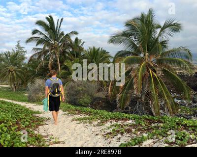 Rückansicht eines Mannes mit Rucksack beim Spazierengehen am Makalawena Beach, Kalaoa, Hawaii, USA Stockfoto
