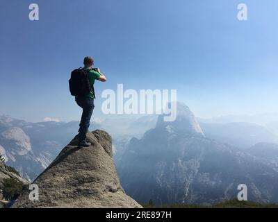 Rückansicht eines Mannes, der Half Dome vom Glacier Point, Yosemite Valley, Yosemite National Park, Kalifornien, USA fotografiert Stockfoto