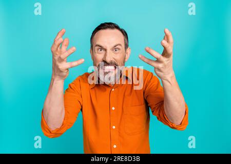Foto eines wütenden, verrückten Kerls, das orangefarbenes Hemd trägt, die aufsteigenden Arme schreit Hände isolierter blaugrüner Hintergrund Stockfoto