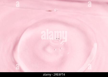 Nahaufnahme eines Wassertropfens mit Wellen und Kopierbereich auf pinkfarbenem Hintergrund Stockfoto