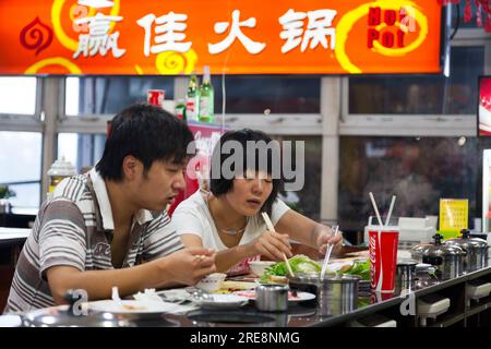 Mahlzeit mit gekochtem Gemüse in einem Hot-Pot-Café, einschließlich kochender chinesischer Blätter/Kochen von Chinakohl, der von einem jungen Paar gegessen wird. Peking, VR China. China. (125) Stockfoto