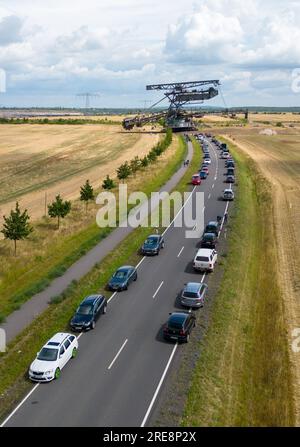 26. Juli 2023, Sachsen, Groitzsch: Ein Schaufelbagger „SRS 1300“ überquert die Bundesautobahn 176 auf dem Weg vom Tagebau Schleenhain zum ca. 10 km entfernten Bergbaufeld Peres. Die Maschine, die gut 1680 Tonnen wiegt, bewegt sich und wird ab dem Herbst weiterhin für den Braunkohlebergbau eingesetzt. Nach Angaben der Mitteldeutschen Braunkohlengesellschaft (Mibrag) ist der Bagger seit Juli 12 in Bewegung und wird am nächsten Montag am Zielort ankommen. Zum Schutz der Straße wurde die Straße mit Planen, Klebebändern und einer Schicht Kiessandmischung abgedeckt Stockfoto