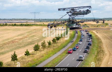 26. Juli 2023, Sachsen, Groitzsch: Ein Schaufelbagger „SRS 1300“ überquert die Bundesautobahn 176 auf dem Weg vom Tagebau Schleenhain zum ca. 10 km entfernten Bergbaufeld Peres. Die Maschine, die gut 1680 Tonnen wiegt, bewegt sich und wird ab dem Herbst weiterhin für den Braunkohlebergbau eingesetzt. Nach Angaben der Mitteldeutschen Braunkohlengesellschaft (Mibrag) ist der Bagger seit Juli 12 in Bewegung und wird am nächsten Montag am Zielort ankommen. Zum Schutz der Straße wurde die Straße mit Planen, Klebebändern und einer Schicht Kiessandmischung abgedeckt Stockfoto