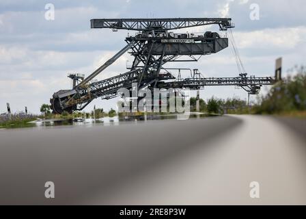 26. Juli 2023, Sachsen, Groitzsch: Ein Schaufelbagger „SRS 1300“ überquert die Bundesautobahn 176 auf dem Weg vom Tagebau Schleenhain zum ca. 10 km entfernten Bergbaufeld Peres. Die Maschine, die gut 1680 Tonnen wiegt, bewegt sich und wird ab dem Herbst weiterhin für den Braunkohlebergbau eingesetzt. Nach Angaben der Mitteldeutschen Braunkohlengesellschaft (Mibrag) ist der Bagger seit Juli 12 in Bewegung und wird am nächsten Montag am Zielort ankommen. Zum Schutz der Straße wurde die Straße mit Planen, Klebebändern und einer Schicht Kiessandmischung abgedeckt Stockfoto