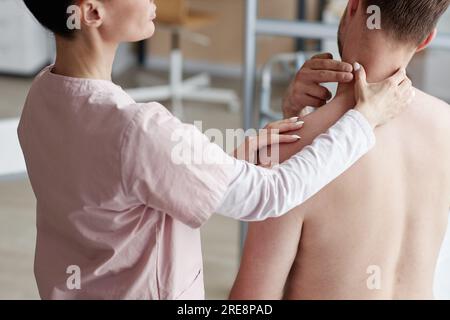 Rückblick des Therapeuten bei der Untersuchung des menschlichen Nackenschmerzes während der ärztlichen Untersuchung im Krankenhaus Stockfoto