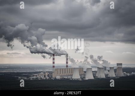 Aus der Vogelperspektive: Kraftwerk, Rauch aus Schornsteinen und Kohlebergwerk in Belchatow unter launischem, wolkigen Himmel, Polen Stockfoto