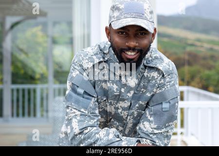 Porträt eines glücklichen afroamerikanischen Soldaten, der Militäruniform auf der Terrasse trägt Stockfoto