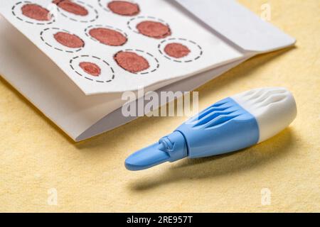 lancet und trockene Blutflecken auf einem Faserfilter zur Laboranalyse, Hausgesundheitstestkonzept Stockfoto