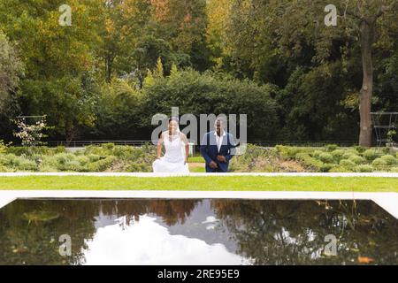 Frohe afroamerikanische Braut und Bräutigam am Hochzeitstag, zusammen im Garten, Kopierbereich Stockfoto