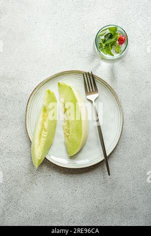 Von oben in eine Keramikschale mit einer Limonade auf Betonhintergrund gebrachte Scheiben von grüner Melone Stockfoto