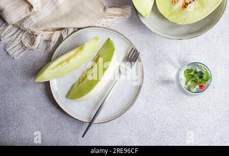 Von oben in eine Keramikschale mit einer Limonade auf Betonhintergrund gebrachte Scheiben von grüner Melone Stockfoto