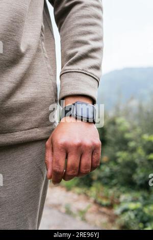 Anonyme Person in Sportbekleidung mit einer Digitaluhr am Handgelenk, die auf einer Landstraße steht Stockfoto