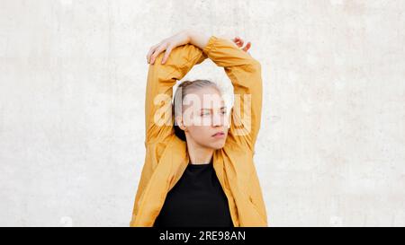 Junge sportliche kaukasische Frau, die sich in der Nähe von Treppen im Freien ausbreitet Stockfoto