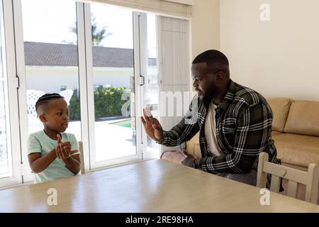 Glücklicher afroamerikanischer Vater und Sohn, die zu Hause Gebärdensprache praktizieren Stockfoto