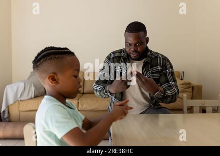 Glücklicher afroamerikanischer Vater und Sohn, die zu Hause Gebärdensprache praktizieren Stockfoto