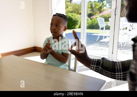 Glücklicher afroamerikanischer Vater und Sohn, die zu Hause Gebärdensprache praktizieren Stockfoto