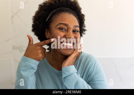 Porträt einer glücklichen afroamerikanischen Frau in Übergröße im Badezimmer Stockfoto