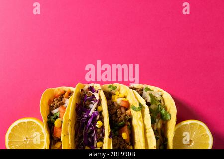 Direkt über Tacos mit Zitronenscheiben vor pinkfarbenem Hintergrund, Kopierbereich Stockfoto