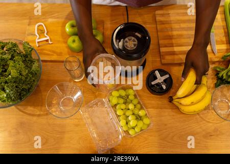 Mittelteil eines afroamerikanischen Mannes, der zu Hause in der Küche gesunden Smoothie zubereitet Stockfoto