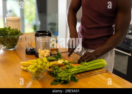 Mittelteil eines afroamerikanischen Mannes, der zu Hause in der Küche gesunden Smoothie zubereitet Stockfoto