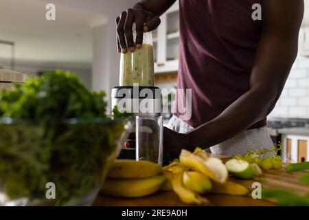 Mittelteil eines afroamerikanischen Mannes, der zu Hause in der Küche gesunden Smoothie zubereitet Stockfoto