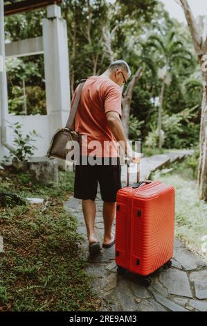 Ein Mann schiebt die Gepäcktasche des Trolleys nach draußen Stockfoto