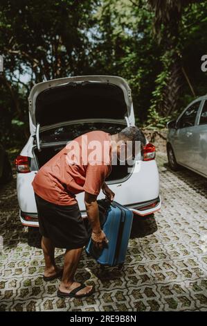 Ein Mann schiebt die Gepäcktasche des Trolleys nach draußen Stockfoto