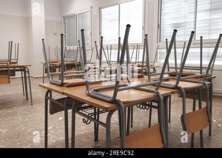 Nahaufnahme ähnlicher umgedrehter Stühle, die nach dem Unterricht auf Holztisch in einem hellen Klassenzimmer in der Schule platziert wurden Stockfoto