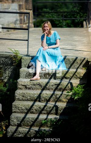 Eine Frau in einem blauen Kleid sitzt auf einer Steintreppe. Stockfoto