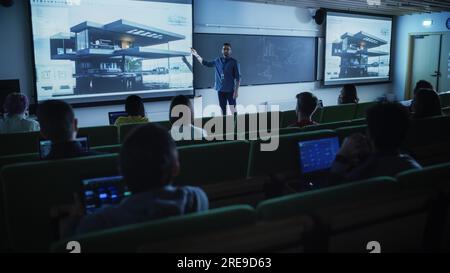 Junger männlicher Lehrer, der einer vielfältigen, multiethnischen Gruppe weiblicher und männlicher Schüler in einem dunklen College-Bereich eine Vorlesung über Datenwissenschaften hält. Dias Projizieren Stockfoto