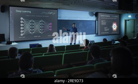 Junger männlicher Lehrer, der einer vielfältigen, multiethnischen Gruppe weiblicher und männlicher Schüler in einem dunklen College-Bereich eine Vorlesung über Datenwissenschaften hält. Dias Projizieren Stockfoto