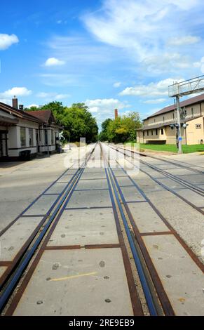 Das historische Eisenbahndepot befindet sich neben den Bahngleisen in Stoughton, Wisconsin. Die Spuren verschwinden in die Ferne. Stockfoto