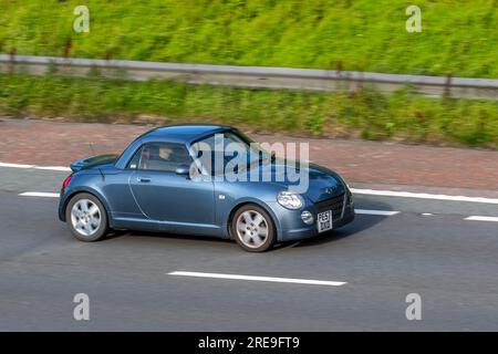 2007 Blue Grey Daihatsu Copen DVVT Auto Roadster 1298 ccm, flippiges kleines Cabrio, 2-türio Kei Auto mit Metalldach, fährt auf der Autobahn M6 in Greater Manchester, Großbritannien Stockfoto