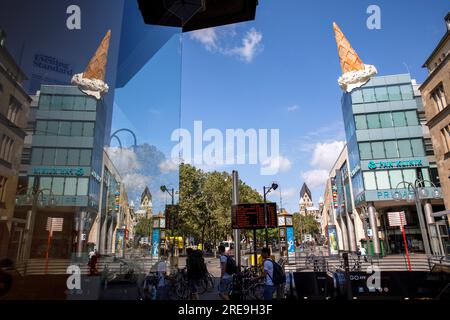 Eiskrem vom Popart-Künstler Claes Oldenburg auf der Spitze des Einkaufszentrums Neumarkt Galerie, Reflexion im Schaufenster, Köln, Deutschland. Eistuete de Stockfoto
