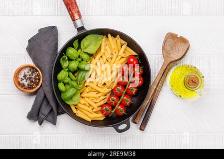 Eine lebendige Darstellung der italienischen Flagge mit Pasta, Basilikum und Tomaten, wunderschön präsentiert in einer Pfanne. Flach verlegt Stockfoto