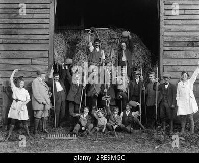 Horace Nicholls - Erwachsene und Kinder, die auf Bauernhöfen tätig sind, und deutsche Kriegsgefangene vor einer Scheune auf einem Bauernhof im Jahr 1918, Suffolk, England, Großbritannien Stockfoto