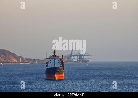 Ein großes Handelsschiff ankerte am Hafen und wartete darauf, geladen zu werden Stockfoto