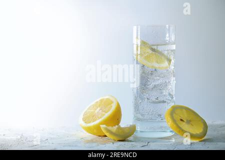 Kohlensäurehaltiges Sodawasser mit Eiswürfeln und Zitrone in einem Trinkglas, erfrischendes Getränk vor hellgrauem Hintergrund, Kopierbereich, ausgewählter Fokus, text Stockfoto