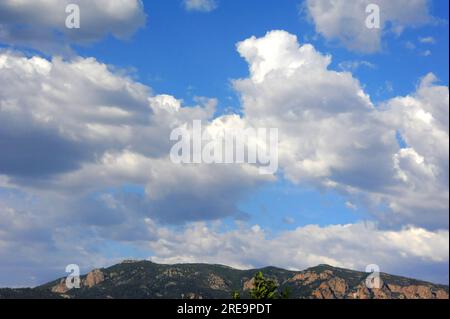 Landschaftsbild der zerklüfteten Sandia Mountains aus Albuquerque, New Mexico. Der Himmel ist hellblau mit angesammelten Wolken. Stockfoto