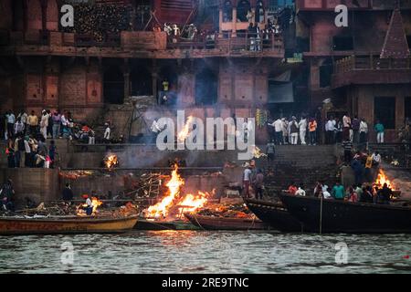 Die Menschen bereiten in Varanasi am Ufer des Ganges, einer der ältesten bewohnten Städte der Welt und die heiligste der sieben heiligen Städte des Hinduismus, Scheiterhaufen vor. Jeden Tag werden in Manikarnika Ghat, dem größten und vielversprechendsten Einäscherungsghat, rund 100 Leichen auf Holzscheiterhaufen am Flussufer eingeäschert. Die ewige Flamme, die die Feuer nährt, soll seit Jahrhunderten brennen. Varanasi, Indien. Stockfoto