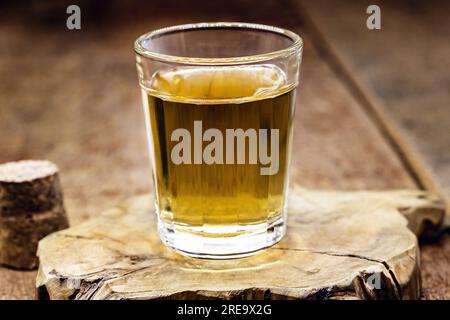 Ein Glas destilliertes alkoholisches Getränk auf Holzhintergrund mit Platz für Text. Ruf nach Rum oder Cachaca Stockfoto