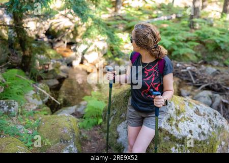 Seniorin wandert durch den Wald und ruht sich auf einem großen Stein aus, Guadarrama, Madrid. Stockfoto