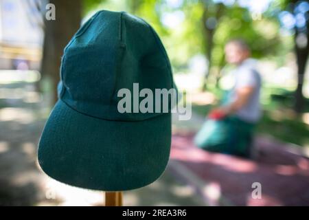 Die grüne Baseballmütze eines Bauarbeiters hängt an einem Holzhaken. Stockfoto