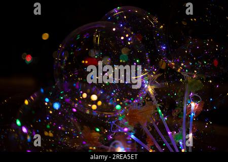 Farbige Kugeln mit hellen Lampen auf dunklem Hintergrund. Textur von Lichtern im Dunkeln. Details zum Feiertag. Weihnachtsdekoration. Heller Hintergrund für C Stockfoto