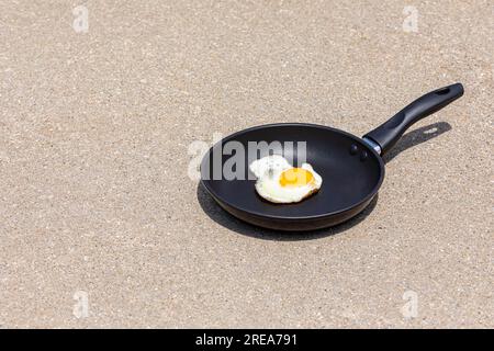 In der Bratpfanne auf dem Gehweg in der Sonne während der Hitzewelle Eier kochen. Warn-, Hochtemperatur- und Hitzewarnkonzept. Stockfoto