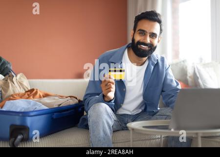 Ein Araber mit Kreditkarte sitzt in der Nähe des Laptops zu Hause Stockfoto