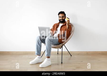 Eastern Man Tätigt Zahlungen Mit Laptop, Auf Dem Die Kreditkarte Im Innenbereich Angezeigt Wird Stockfoto