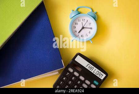 Business- und Economy-Konzept. Auf dem Tisch sind Ordner, eine Uhr und ein Taschenrechner mit der Aufschrift "FHA LOAN" Stockfoto