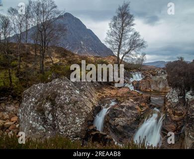 Stürmische Szene des Buachaille Etive Mor, Berg in Glencoe, Schottland, mit sanftem Wasserfall im Vordergrund Stockfoto